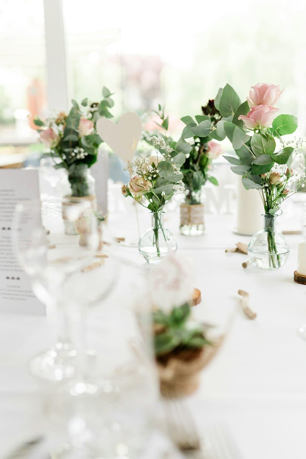 Small glass bud vases with single stems on a white table